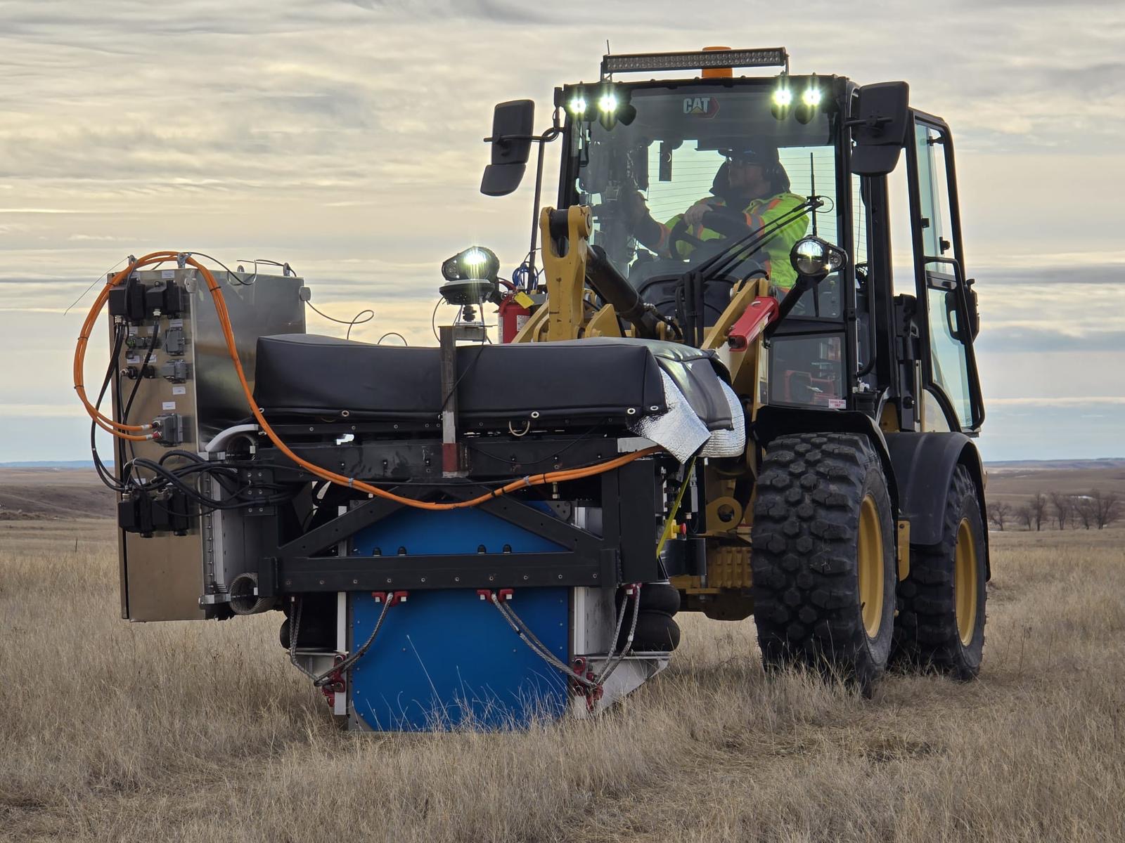 Close-up of low-impact vibroseis source unit mounted on a compact wheel loader on the prairies